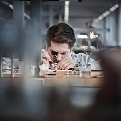 A watchmaker adding elements to a mechanical watch