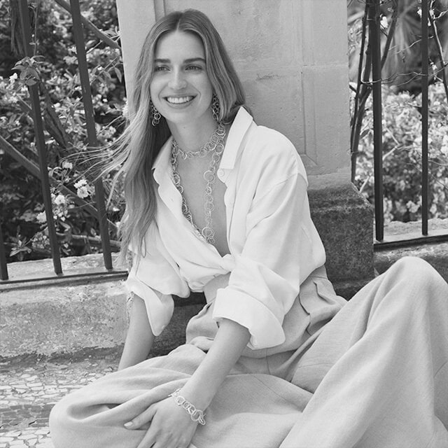 Outside black and white visual of a smiling woman wearing a white outfit