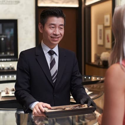 A man showing a mechanical watch to a customer in a boutique